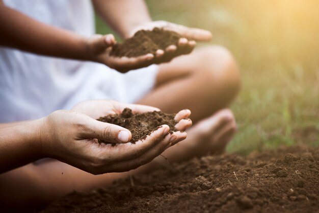 Enfant et parent tenant le sol et préparant le sol pour la plantation de l'arbre