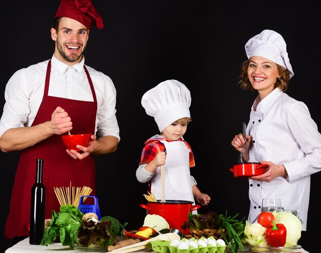 Enfant avec des parents cuisinant à table de cuisine famille aimante heureuse préparant le dîner ensemble fait maison