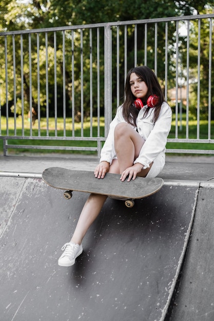 Enfant patineur avec planche à roulettes et casque assis sur une rampe de sport Mode de vie sportif extrême Publicité créative pour le magasin de sport pour enfants