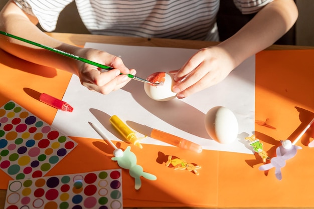 L'enfant peint la créativité d'oeufs blancs avec des mains d'enfants filles avec des oeufs sur le fond d'une table w