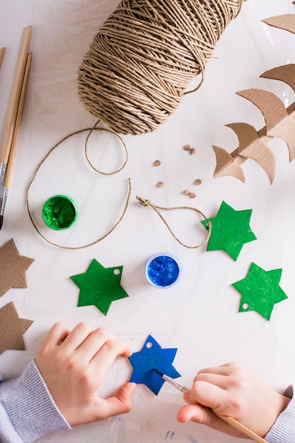 Un enfant peint une étoile à la gouache à partir de carton pour les décorations de Noël DIY Vue de dessus et verticale