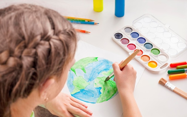 Un enfant peint un globe avec des aquarelles