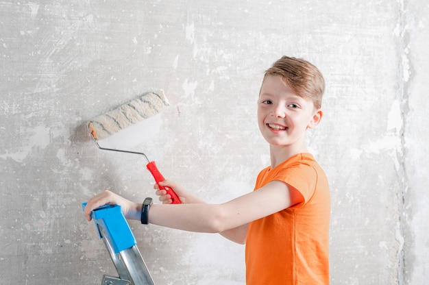 l'enfant peint un mur bleu avec une réparation de rouleau