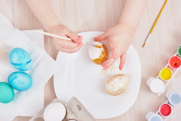 Photo enfant peint oeuf de pâques sur une table en bois