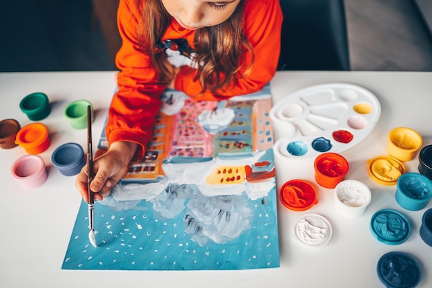 Un enfant peint un paysage d'hiver du Nouvel An