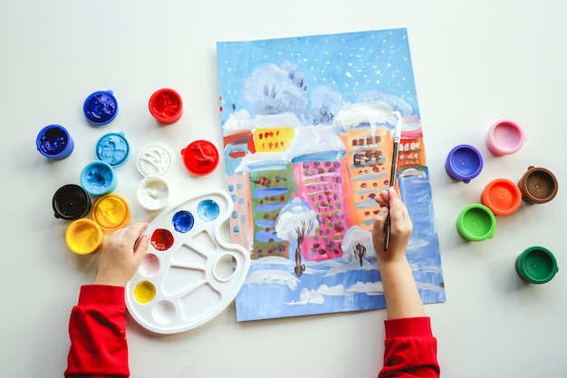 Un enfant peint un paysage d'hiver du Nouvel An