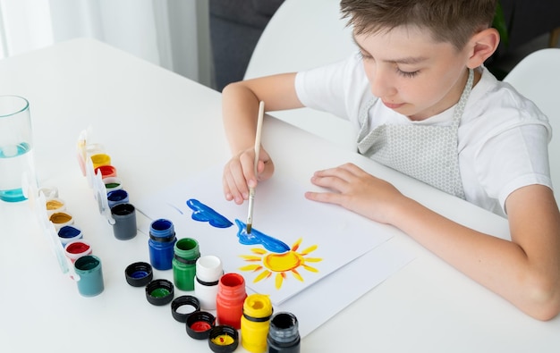 L'enfant peint des pinceaux de peinture à la gouache à l'aquarelle des autocollants de crayons de couleur et de cire Ensemble pour dessiner la créativité et les loisirs