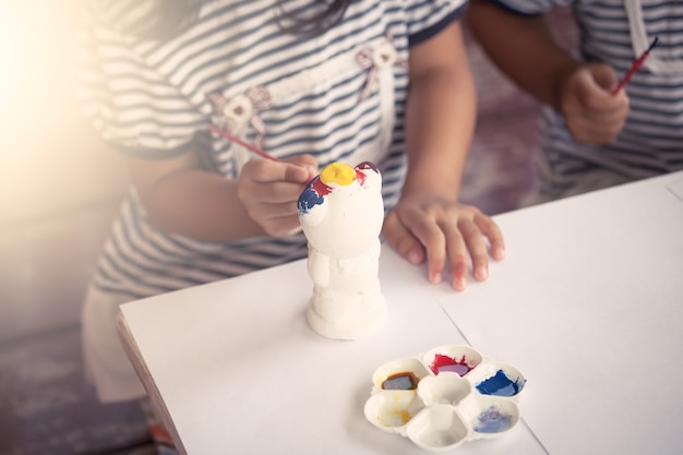 Enfant peinture petite fille s&#39;amuser à peindre sur une poupée de stuc