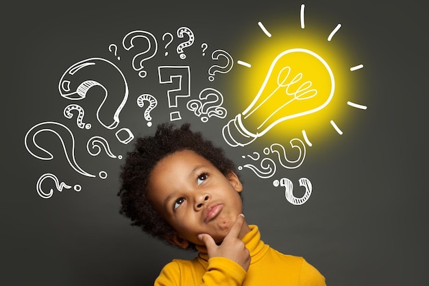 Enfant pensant garçon sur fond noir avec ampoule et points d'interrogation Brainstorming et concept d'idée