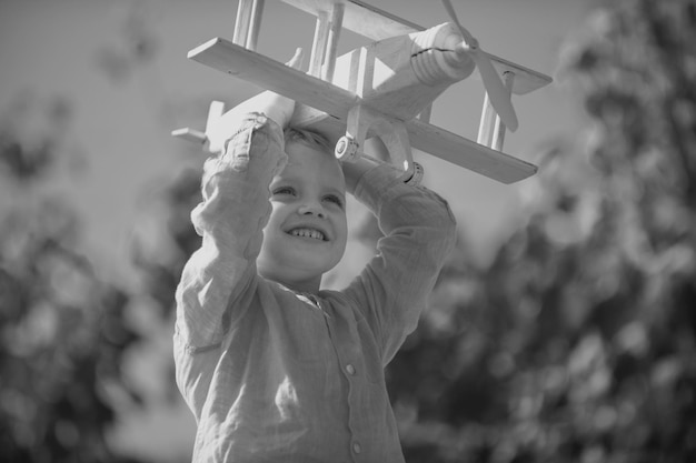 Un enfant pilote avec un avion jouet rêve de voyager en été dans la nature les enfants rêvent que l'enfant joue avec un