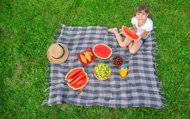 Un enfant en pique-nique mange une pastèque