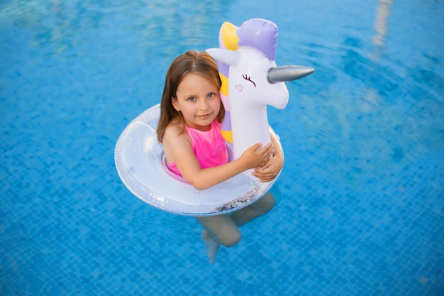 Enfant en piscine sur anneau violet gonflable licorne