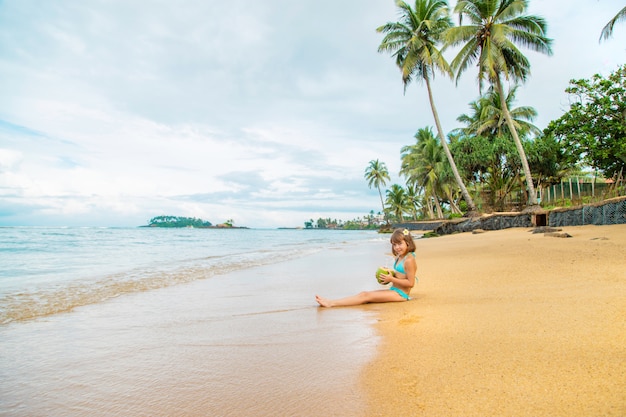 Un enfant sur la plage boit de la noix de coco.