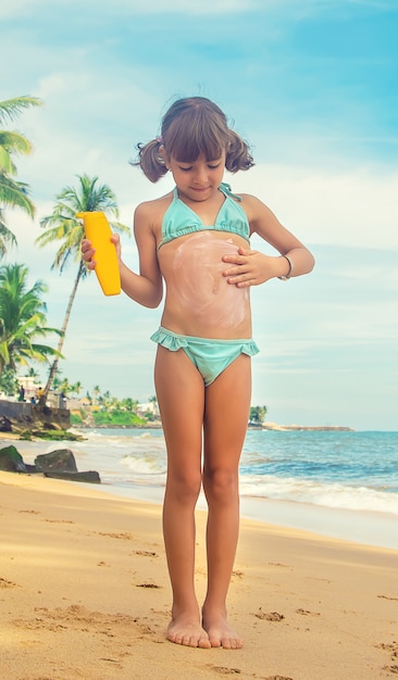 Enfant sur la plage avec un écran solaire sur le dos