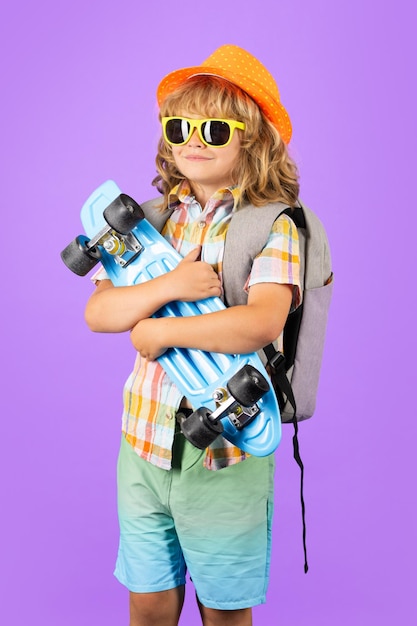 Enfant avec planche à roulettes sur fond de studio violet Enfant tenir une planche à roulettes Sport et activité sains