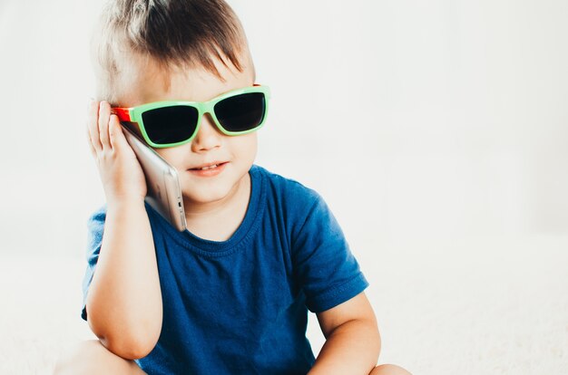 Enfant portant des lunettes de soleil avec smartphone, concept d'entreprise