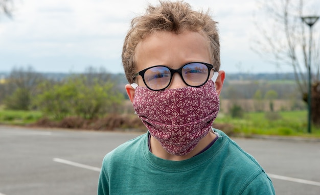 Enfant portant un masque anti-virus à l'extérieur