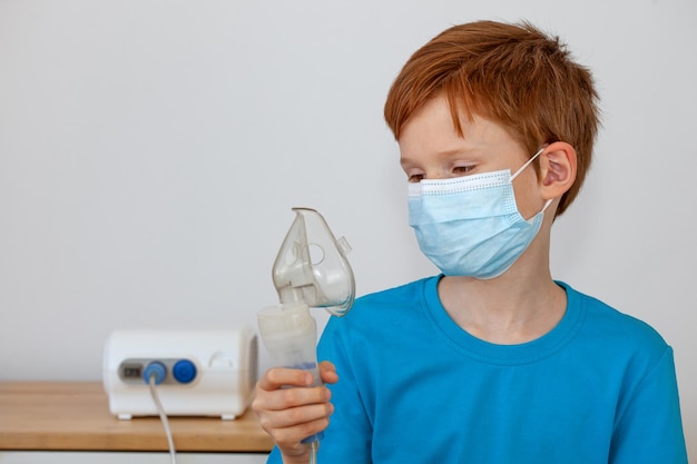 Un enfant portant un masque médical tient un nébuliseur dans ses mains Concept de traitement de la toux covid19