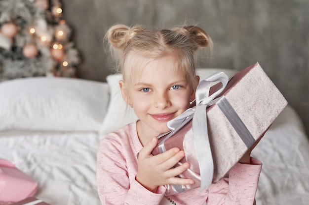 Enfant portant un pyjama et ouvrant le cadeau de Noël