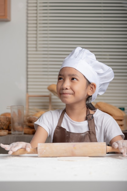 Un enfant portant une toque blanche et souriant de bonheur.