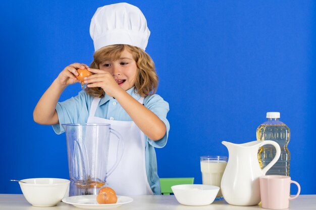 Enfant portant un uniforme de cuisinière et un chapeau de chef préparant des légumes sur la cuisine studio portrait cuisson cu