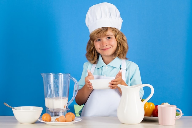 Enfant portant un uniforme de cuisinière et un chapeau de chef préparant des légumes sur un portrait de studio de cuisine Cuisine culinaire et concept de nourriture pour enfants