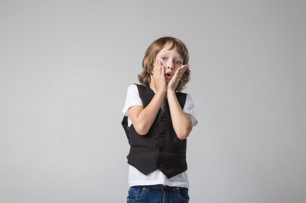 Enfant posant émotionnellement à la caméra dans le Studio sur fond blanc