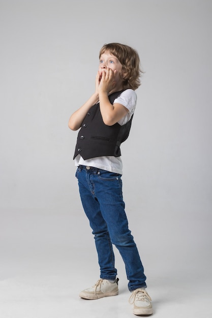 Enfant posant émotionnellement à la caméra dans le Studio sur fond blanc