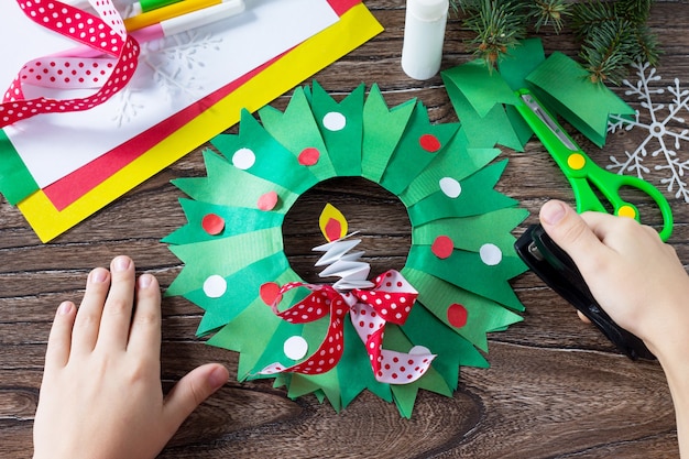 L'enfant pose les détails de la couronne de Noël avec une bougie