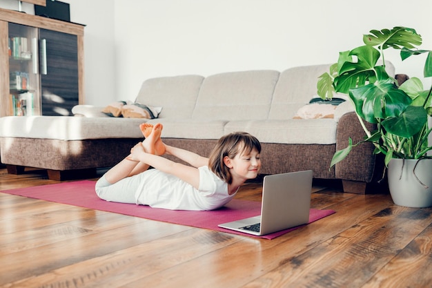 L'enfant pratique et apprend le yoga à la maison la fille s'entraîne au sport dans la vie des enfants