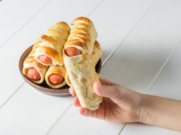 L&#39;enfant prend une saucisse maison dans la pâte du bol. La vue du haut.