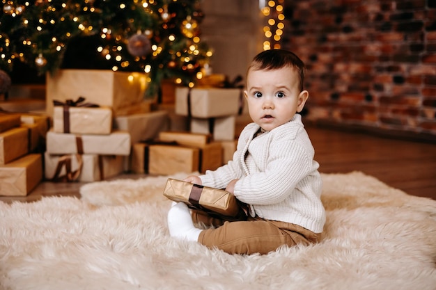 enfant près de l'arbre de noël avec un cadeau