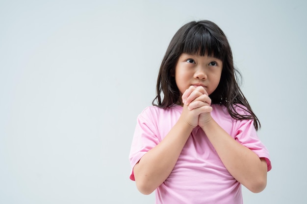 L'enfant prie les mains jointes en prièrexA