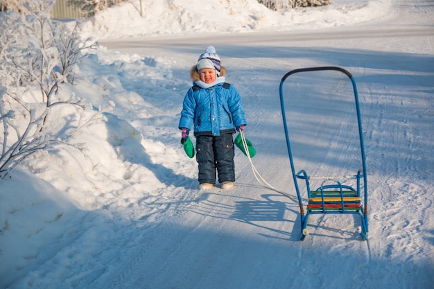 Enfant de quatre ans sur la neige avec traîneau.