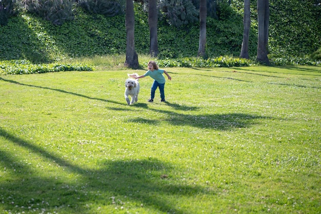 Enfant qui court avec un chien enfant avec un chien chiot jouant en plein air sur la pelouse de l'arrière-cour enfance insouciante