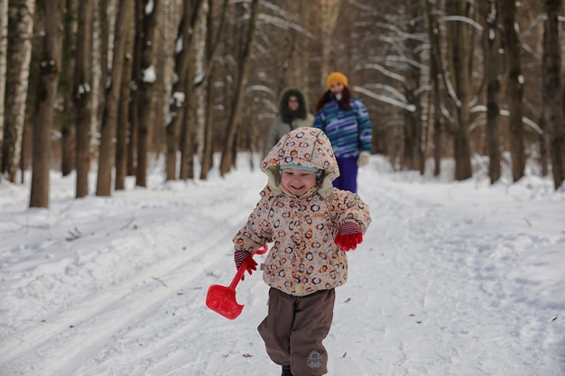 Photo enfant qui court dans un parc d'hiver et s'amuse en famille
