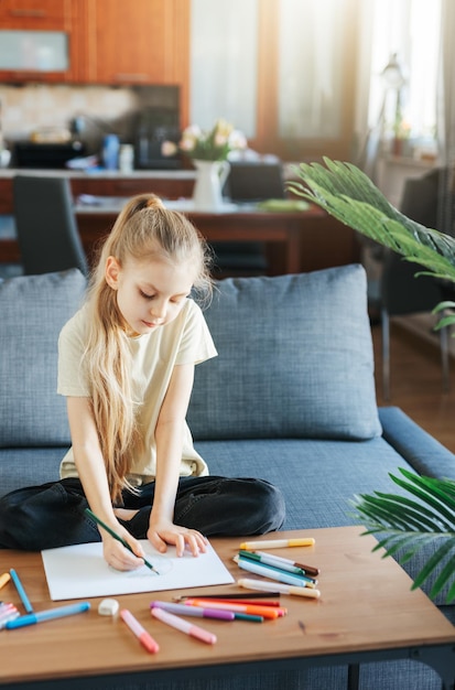 Une enfant qui dessine avec des crayons colorés