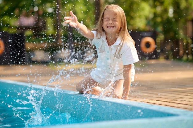 Enfant qui joue. Jolie fille blonde jouant près de la piscine