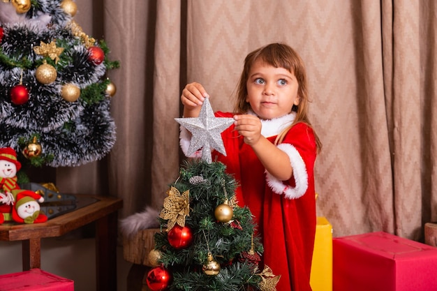 Un enfant de race blanche organise la décoration de l'arbre de noël avec un concept d'idées festives de noël amusant et joyeux