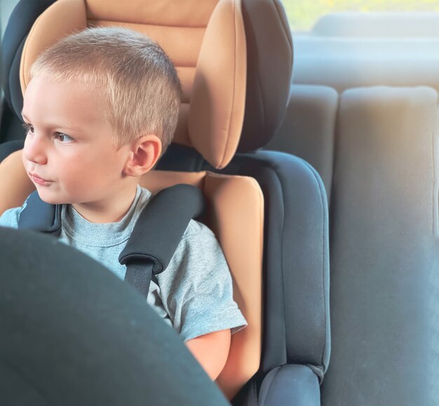 Enfant de race blanche sur un siège auto noir avec un centre de pêche. Concept de sécurité automobile, location de voiture avec un enfant.