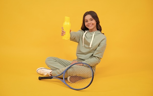 Enfant avec raquette de tennis adolescente boire de l'eau après l'entraînement sportif joueur de badminton se détendre