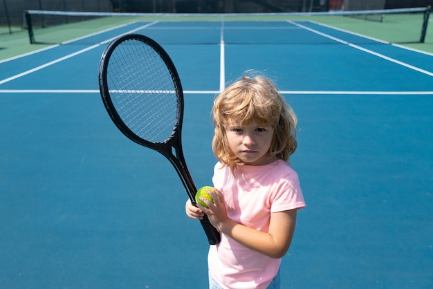 Enfant avec raquette de tennis et balle sur un court de tennis extérieur. Exercice de sport pour les enfants. Activités estivales pour les enfants. Formation pour jeune enfant.