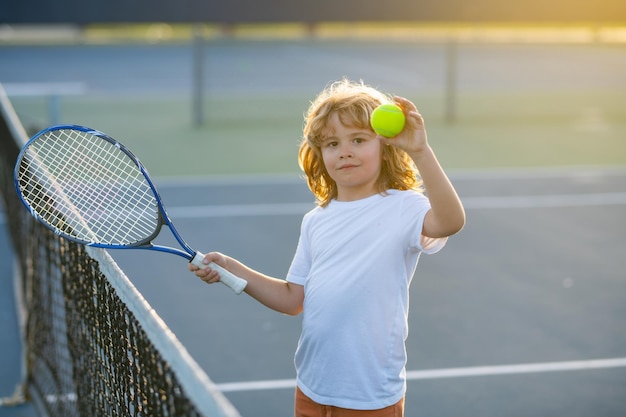 Un enfant avec une raquette de tennis et une balle de tennis jouant sur un court de tennis