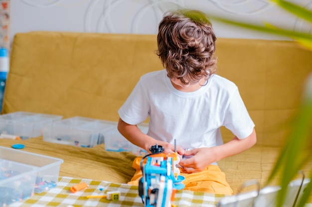 Photo un enfant récupère un robot à partir de détails en plastique et programmé sur la robotique de la tablette