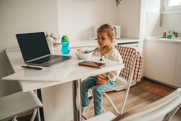 Enfant réfléchi assis au petit-déjeuner dans la cuisine