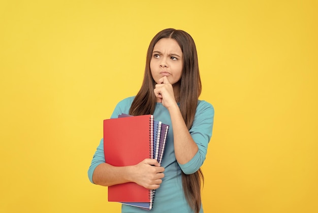 Une enfant réfléchie tient un bloc-notes pour l'école des devoirs