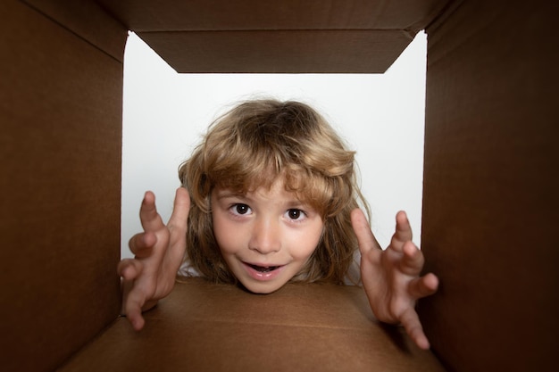 Enfant regardant à l'intérieur de la vue de dessous de la boîte en carton livrant votre achat les enfants célèbrent l'anniversaire birt