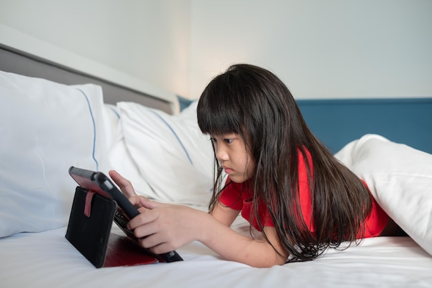 Enfant regardant une tablette sur le lit dessin animé enfant accro