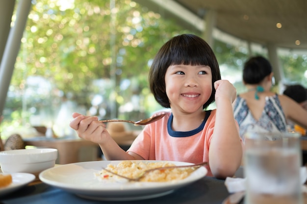 Enfant regardant la tablette sur la table de la nourriture, dessin animé pour enfants accro