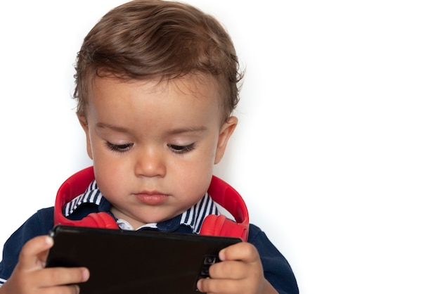 Enfant regardant des vidéos sur téléphone mobile avec un casque rouge et une chemise bleu foncé